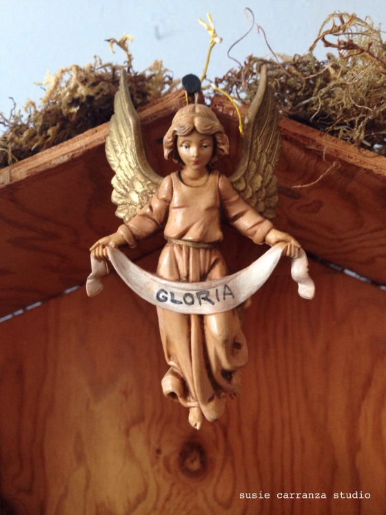 Gloria angel hangs at center of manger...